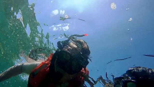 mama e hijo practicando snorkel en las islas gal&aacute;pagos visten chaleco salvavidas, mascara de snorkel