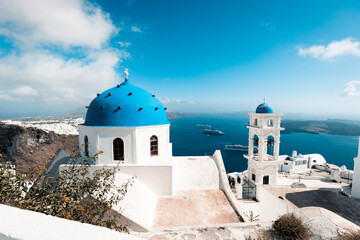 magical and sun covered city of thira, ideal for vacation and travel during hot summer days, on the horizon the sea and beautiful roofs of houses, travel and relaxation in greece,white and blue 