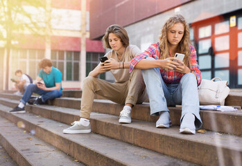 Boy and girl playing on smartphones during recess between college classes