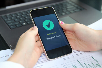 Woman using online banking on mobile phone. Payment sent.