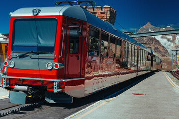 Fototapeta premium Alps high mountain train station with red train