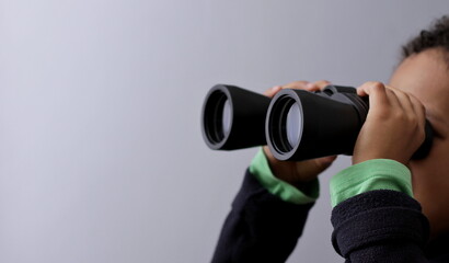 boy looking  through binoculars on grey background stock photo 