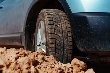 Car wheel standing offroad on stones and sand close-up view