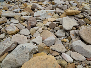 Stones on the beach tecsture, big light brown and gray boulders.