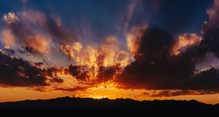 Fototapeta premium Colorful red dramatic sky at sunset light with mountains silhouettes