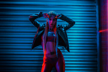 Young woman dancer posing in dark night club interior with neon lights