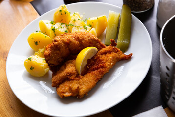 Parmesan breaded chicken schnitzel with garnish of boiled potatoes with fresh parsley and pickles....