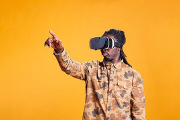 Positive man enjoying virtual reality headset experience, playing with virtual reality glasses to see 3d visual simulation. African american person wearing modern goggles to use futuristic technology.