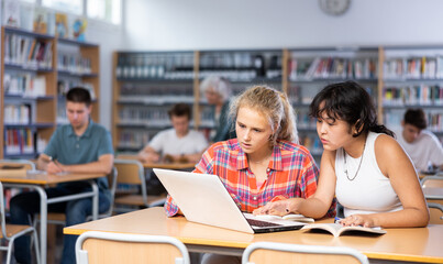 Fototapeta na wymiar Teaching teenagers in the school library using a laptop