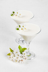Vegan Vanilla cream jelly dessert, Panna Cotta, decorated with small white flowers, in a martini glass. White background