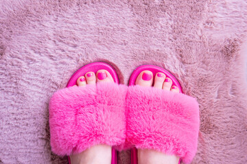 Fototapeta na wymiar feet in pink fur house slippers on powdert carpet