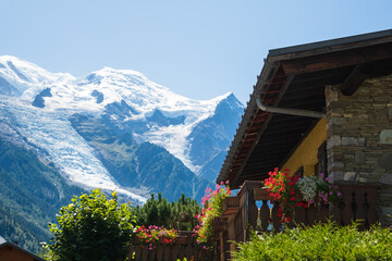 Chamonix-Mont-Blanc, France. Beautiful Alpine landscape with snow covered Mont Blanc mountain in summer and traditional chalet house at foreground. Haute-Savoie tourism.  Europe vacation destinations. - obrazy, fototapety, plakaty