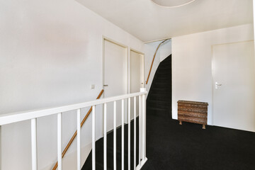 a stairway way in a house with black carpet and white trim on the stairs, leading up to the second floor