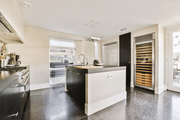 a modern kitchen with black and white appliances on the counters, along with an open door leading to another room