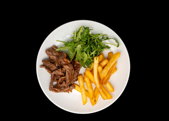 Stir-fried beef served with french fries and arugula leaves on white plate, isolated on black background. Top view or flat lay.