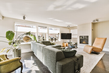 a living room with couches, chairs and a fire place in the center of the room is large windows