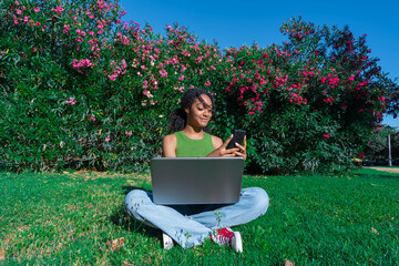 Smartphone y computadora port&aacute;til  con una mujer joven usando aplicaci&oacute;n en tel&eacute;fono m&oacute;vil inteligente y sonriendo feliz. Mensajes de texto y video de hermosa chica multirracial o usando la aplicaci&oacute;n