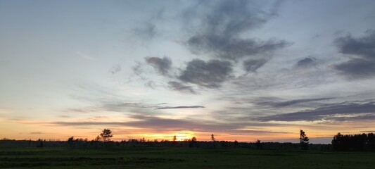 Spring sunset over the field. The sun has gone below the horizon, its last rays are visible. There...