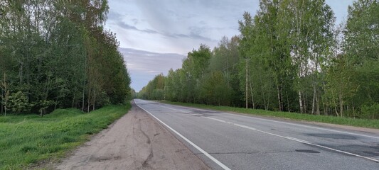 Country asphalt road. On a spring evening, a gray strip of asphalt highway goes into the distance....