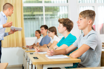 Obraz premium Pupils sitting in class and listening carefully to male teacher.