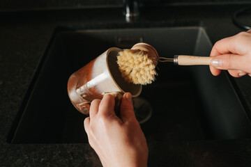  Mugs cleaning with a brush.Ecofriendly housekeeping and dishwashing.Zero waste. hands wash a...
