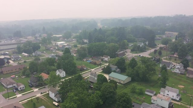 An orbiting parallax aerial view of the small unincorporated town of Masury, Ohio. Foggy view due to the Canadian wildfires of 2023.  	