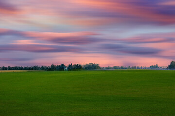 View from road trip landscape with field. Green fields and orange sky during the sunset,