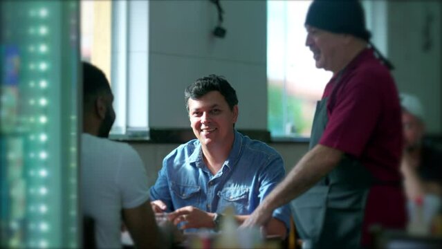 Candid Interaction between Customer and Waiter at Restaurant. Casual conversation of client with server at traditional cafeteria in South America