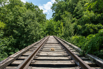 Fototapeta premium Straw hat sitting alone on a railroad track in the forest on a sunny day