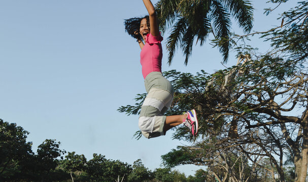 latina woman enjoying, jumping high. feeling free, joyful, excited outdoors.