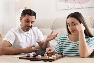 Couple playing checkers at table in room