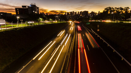 Trail of light caused by vehicular traffic in Highway with buildings from downtown in the background, in Marília,