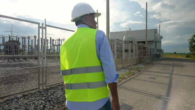 Senior electrical engineer visits a wind turbine power plant for inspection and assessment. Electricity production industry, sustainable clean energy concept