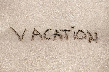 Word vacation written on the sand