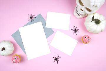 Pink Halloween 5x7 and 2 half cards greeting card, party invitation mockup. Trick or treat party supplies styled with white skull, pumpkins, black spiders, and spooky cupcakes. Negative copy space.