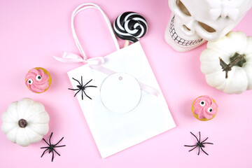 Pink Halloween round gift tag party favor mockup. Trick or treat party supplies stationery styled with white skull, pumpkins, black spiders, and spooky cupcakes. Negative copy space.