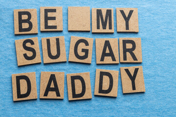 Sign formed with small pieces of wood with the text "be my sugar daddy".