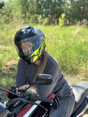 young woman in a helmet and gloves on a motorcycle