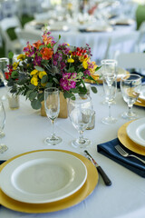 Table setting for wedding event with glass, chargers and colorful flowers