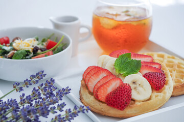 A Plate of Waffles toped with Strawberries and Bananas, small salad for Break