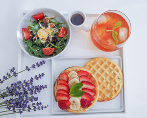 A Plate of Waffles toped with Strawberries and Bananas, small salad for Break
