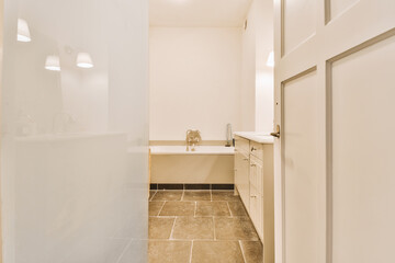 a bathroom with white walls and beige tile on the floor, there is an open door leading to another room