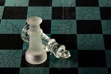 Checkmate - Chessboard cracked with the defeated king submitting to the queen's checkmate. Glass...