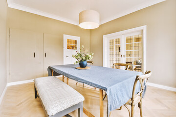 a dining room with a blue table cloth on it and a bench in the middle of the room that is empty