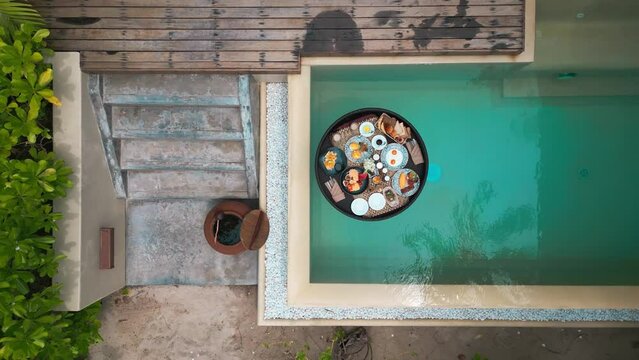 Top view of luxury floating breakfast in private pool. Special menu with floating pool tray for exotic summer vacations. Floating breakfast tray contains food and beverage is drifting in pool