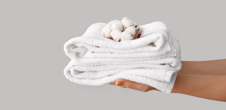 Female hands with cotton flowers and soft towels on light background