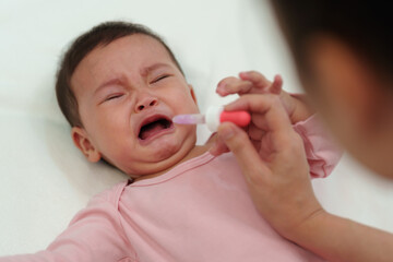 sick infant baby crying while refuses eating liquid medicine with dropper