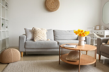 Interior of modern living room with cozy sofa and flower vase on coffee table