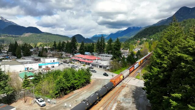 Industrial Train Running On Railway In Hope, BC, Canada. aerial ascend