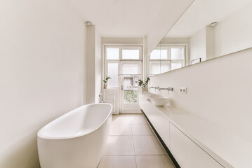 a bathroom with a bathtub and sink in the fore, taken from the side to the other part of the room
